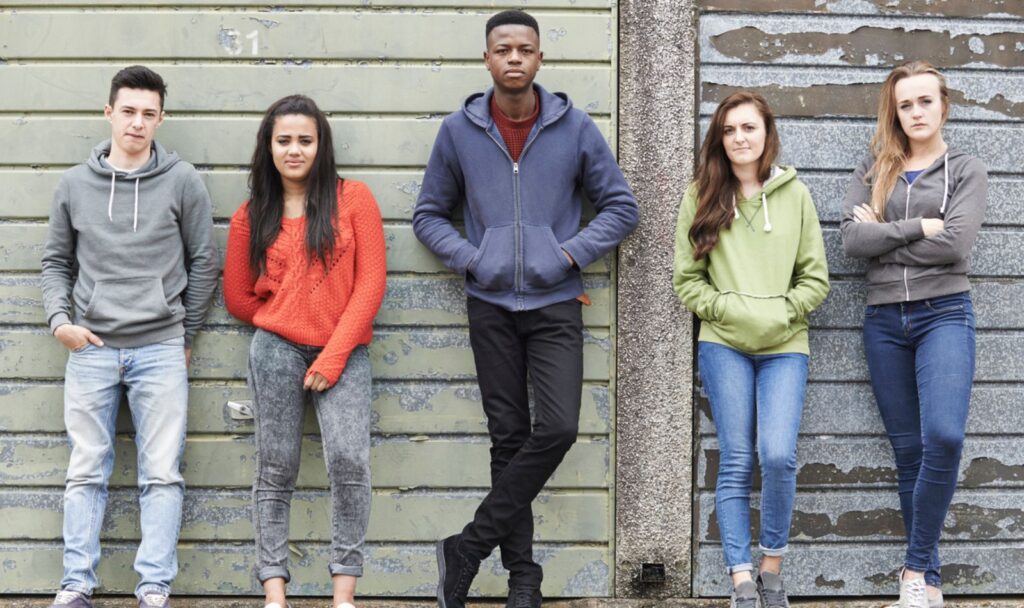 A group of teenagers standing side by side looking at the camera